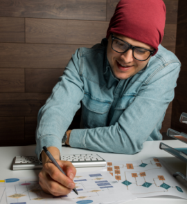 A person in long sleeve shirt sits and writes.